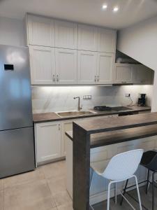 a kitchen with white cabinets and a stainless steel refrigerator at Kate Apartments in Kokkari