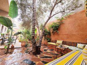 a patio with a tree and a couch and tables at Hôtel&Restaurant Villa des étoiles in Ourika