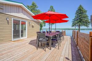 a wooden deck with a table with chairs and a red umbrella at La vie O-Lac Magog in Sherbrooke