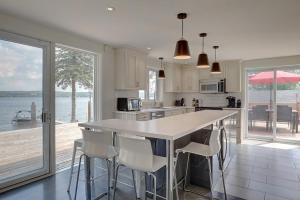 a kitchen with a large island with white counter chairs at La vie O-Lac Magog in Sherbrooke