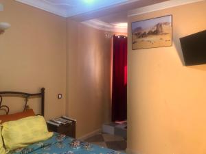 a bedroom with a bed and a tv on the wall at Le Garden Ghardaia in Ghardaïa
