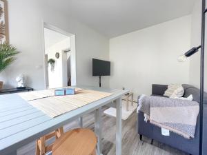 een woonkamer met een tafel en een blauwe bank bij Les chats pitres Maison au calme rénovée avec jardin, terrasse aménagée, transats, abri à vélo, parking gratuit, 5 mn à pied du centre Bayeux proche des plages du débarquement in Bayeux