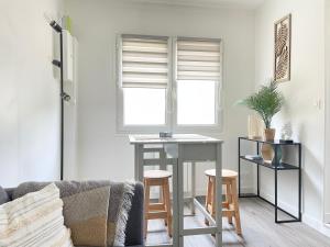 een woonkamer met een tafel en 2 krukken bij Les chats pitres Maison au calme rénovée avec jardin, terrasse aménagée, transats, abri à vélo, parking gratuit, 5 mn à pied du centre Bayeux proche des plages du débarquement in Bayeux +45 foto's