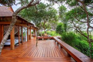a wooden deck with a bed and a bench on it at Aloha 15 Cottage in Ponta Mamoli