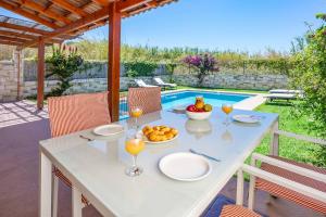 una mesa con copas de vino y un bol de fruta en Villa Mandarin Platanias, en Plataniás