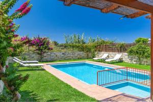 Una piscina en un patio con sillas y flores. en Villa Mandarin Platanias, en Plataniás