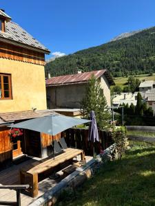 d'une terrasse avec un parasol et une table en bois. dans l'établissement BEAU CHALET DE MONTAGNE SERRE CHEVALIER AU PIED DES PISTES PLEIN SUD, à La Salle Les Alpes