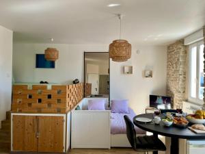 a living room with a table and a bedroom at Logement chaleureux et lumineux avec pierres apparentes à l'Étang au Duc - L'ÉCRIN BRETON in Vannes