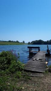 a picnic table and bench on a dock on a lake at Studio LIMES in Zatonje