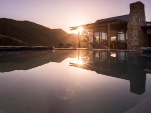 a house with a pool with the sunset in the background at Ludicks Farm in Montagu
