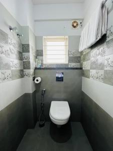 a bathroom with a white toilet and a window at Hotel Abhimaani Vasathi, Rajajinagar in Bengaluru