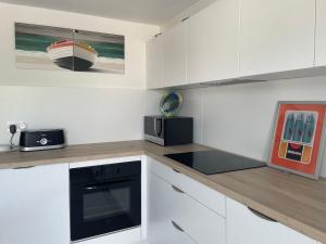 a kitchen with white cabinets and a black appliance at Le STUDIO in Barbâtre