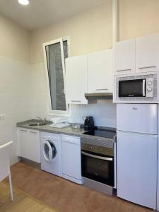 a kitchen with white cabinets and a washer and dryer at Marinera in Luarca +5 photos