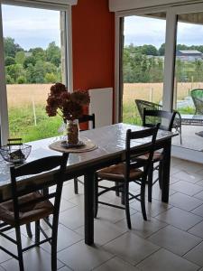 a dining room table and chairs with a view of a field at la clé du bouton d'or in Leschelles +39 photos