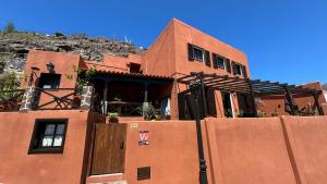 a red brick building with a fence in front of it at Casa Moni con Vistas al Mar in Playa de Santiago