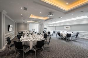 a conference room with tables and chairs and a screen at Gem Fitzrovia Hotel in London