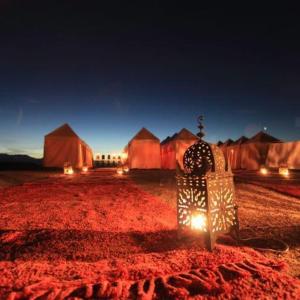 a group of tents with lights in the desert at night at Agafay country club in Tafza