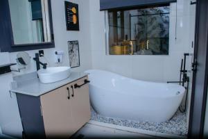 ein Badezimmer mit einer weißen Badewanne, einem Waschbecken und einer Badewanne in der Unterkunft G-Pinnacle Signature in Ilorin + 37 Fotos
