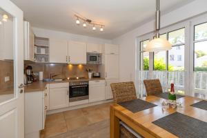 a kitchen with white cabinets and a table with chairs at Strandvilla Luv Lee Miramar in Rerik