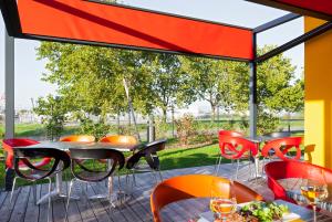 un patio con tavoli, sedie e una grande finestra di Best Western Colmar Expo a Colmar