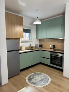 una cucina con armadi verdi e un tappeto sul pavimento di Enjoy Shkodra Apartment a Shkodër