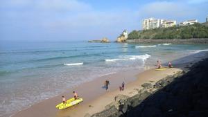 un groupe de personnes sur une plage avec des planches de surf dans l'établissement biarritz cote des basques VUE SUR MER, à Biarritz