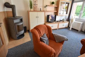 un soggiorno con una sedia arancione e una stufa di 2020 Bungalow "Strandhüdde" a Dahme