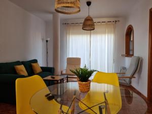 a living room with yellow chairs and a glass table at Torete in Roquetas de Mar