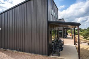 a metal building with chairs on a patio at Willie In the Hill Country - Hacienda Amor in Johnson City +7 photos