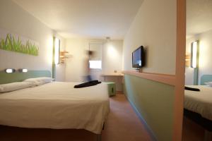 a hotel room with two beds and a flat screen tv at ibis budget Saint Paul Les Dax in Saint-Paul-l&egrave;s-Dax