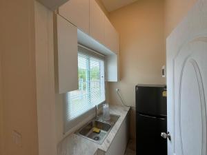 a kitchen with a sink and a black refrigerator at Villa Lacroix Organic Farm in San Pa Tong
