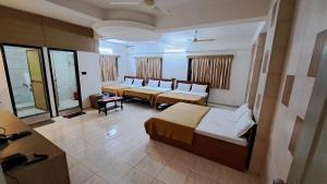 特里姆巴克Hotel Dhruv Palace的酒店客房设有三张床和一张桌子