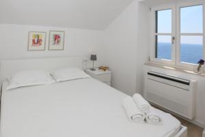 biała sypialnia z dużym łóżkiem i oknem w obiekcie White & Co Villa And Apartments w Dubrowniku