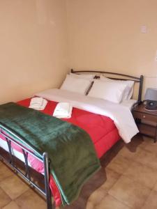 a bedroom with a bed with red and white sheets at LittleParadise100MFromTheBeach in Áyioi Apóstoloi