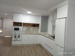 a white kitchen with white cabinets and appliances at Trafalgar Royal in Adra