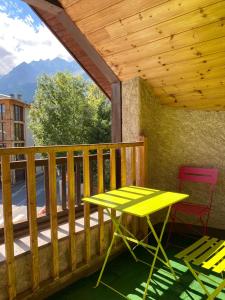 a yellow table and chairs on a deck with a wooden ceiling at Superbe duplex cosy au cœur de Mônetier Les Bains in Le Monêtier-les-Bains +34 photos