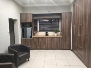 a kitchen with wooden cabinets and a chair in a room at Preller Accommodation in Bloemfontein