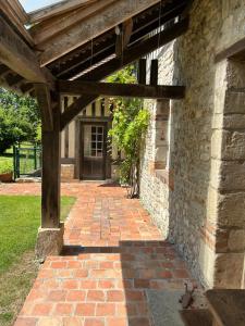 a brick walkway leading to a building with a wooden pergola at Les Maisons de Marie in Manerbe