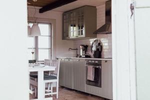 a kitchen with a stove and a sink and a table at Bagarstugan på Grindtorp in Enköping