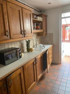 a kitchen with wooden cabinets and a microwave at 35 Holborn road London E13 8PH Near EXCEL EXHIBITION CENTRE in London