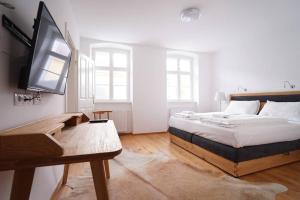 Authentic Austrian Flat in the South of Vienna في مودلينغ: غرفة نوم مع سرير ومكتب مع تلفزيون