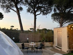 a patio with a table and chairs and trees at Bulle insolite avec jacuzzi privé - Nature & romantisme a Fréjus in Fréjus