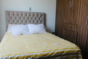 a bed with a yellow and white striped comforter and pillows at Independiente Minidepa Yanahuara in Yanahuara