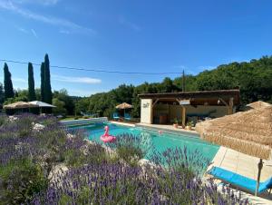 a pool with a pink flamingo in a field of flowers at Les Rocailles in Lamonzie-Montastruc