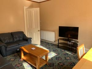 a living room with a couch and a flat screen tv at High Street 2 Bedroom Apartment in Ayr