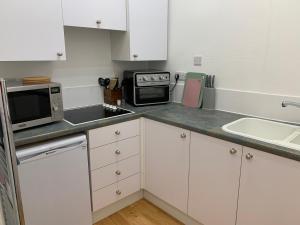 a small kitchen with white cabinets and a microwave at High Street 2 Bedroom Apartment in Ayr