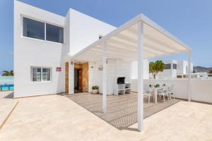 a white house with a patio with a table and chairs at Villa Atlántica - Heated pool in Playa Blanca in Playa Blanca