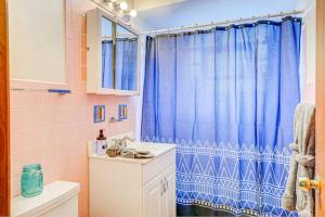 a bathroom with a blue shower curtain and a sink at 90s Condo| King Bed | 65” Smart TV | Arcade Game in Elmwood Park