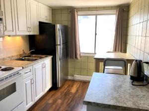 a kitchen with white cabinets and a stainless steel refrigerator at Canterbury Inn in Invermere
