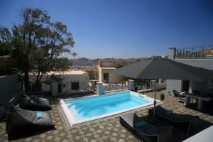 a swimming pool with chairs and an umbrella at Casa Di Soho Syros in Ermoupoli